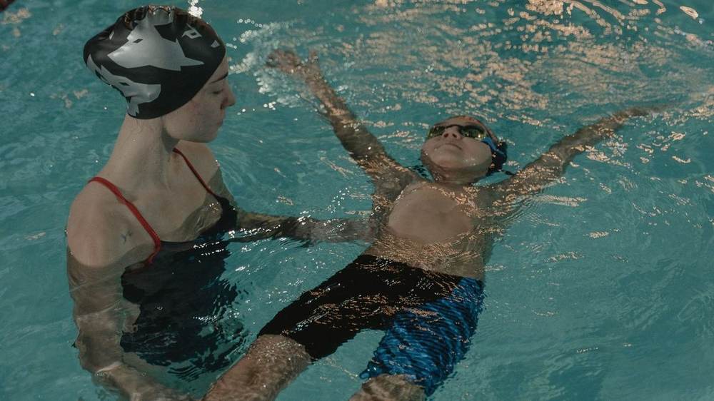 A swim instructor supporting a child practising a back float