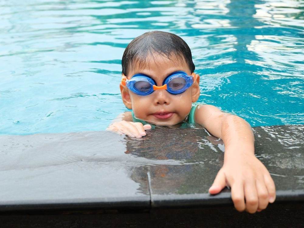 A boy in goggles holding the pool edge